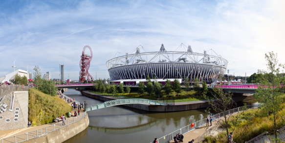 London, England - September 6, 2012: The canals of the Olympic Park in Stratford, London. The London 2012 Olympic and Paralympic Games Stadium is in the background along with the Orbit, a viewing platform. Visitors to the park can be seen walking along the canal pathways.