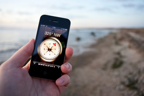 Baltic Shore, Estonia - October 29, 2011. Male hand holding an Apple iPhone 4 smartphone with the Compass App on screen.