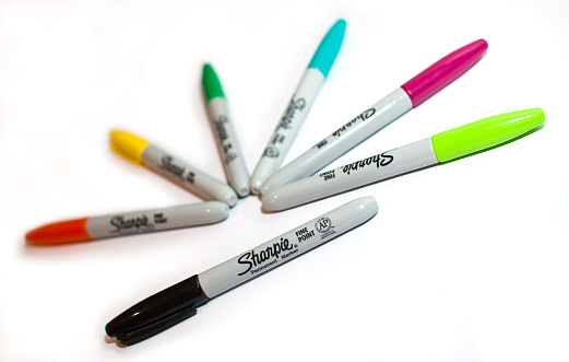 London, UK -- March 20, 2012: Different coloured Sharpie brand marker pens arranged in pattern on a white background with shadows.