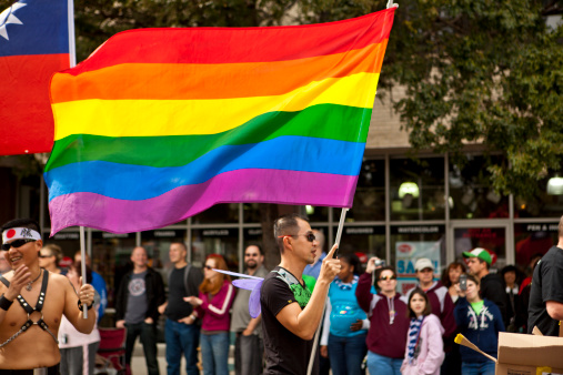 Atlanta, United States of America - October 9, 2011: A male participants lifts a giant rainbow flag as he marches down Peachtree Street in the Atlanta Pride Parade.