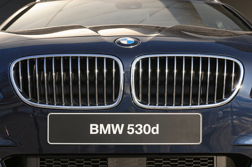 Munich, Germany - February 23rd, 2011: Close up front view showing the radiator grille and numberplate of a new BMW 530d with dark blue metallic paint.