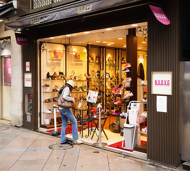 Tokyo, Japan - May 30, 2011: A woman shopper tries on shoes at the sidewalk display of the NUOVO shoestore in the Shinjuku area of Tokyo, Japan.