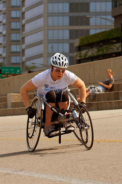 femme dans un fauteuil roulant de course travaille sur chicago lakeshore - sports en fauteuil roulant photos et images de collection