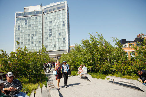 New York, New York, USA - May 12, 2011: People stroll and relax on The Highline elevated park on a bright sunny day. The large building in the background is The Standard Hotel which straddles The Highline. The Highline is an elevated park in the meatpacking district of lower Manhattan. It was built on an old unused elevated freight railway.