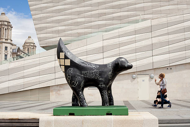 Mini Superlambanana outside the Museum of Liverpool "Liverpool, England- June 30, 2012: Two women walk between the Museum of Liverpool and a Mini Superlambanana art installation on the Pierhead in Liverpool, England. The mini Superlambananas sculptures were an art exhibition in 2008 for Liverpool's City of Culture celebrations." superlambanana sculpture in liverpool stock pictures, royalty-free photos & images