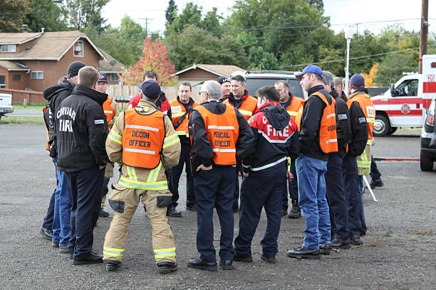 Disaster Team Discussion Ring "Eugene, Oregon, USA aa November 3, 2011: This is a mock chemical spill drill with the various fire departments from Eugene, Lane County, and other nearby emergency services. This group of team members gathers around to discuss options." drill team stock pictures, royalty-free photos & images
