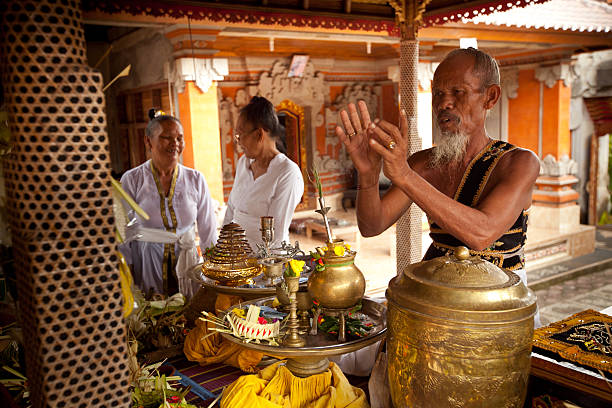 15th October 2024, Ubud,Bali: An Indonesian woman in traditional clothing walking praying to god during Nyatur. In Balinese Hinduism, Nyatur Desa is a sacred ritual performed in various villages, such as Desa Pakraman Ipah in Karangasem and Cau Belayu in Tabanan. This ceremony involves parading sacred effigies (prelingga), like Barong and Rangda, around the village to purify the area and invoke protection from negative energies. It's part of a broader tradition called Mecangcang, where these effigies are enshrined for 42 days in a temporary shrine outside the main temple. During the Nyatur ritual, offerings such as segehan agung and animal sacrifices are made to deities like Ida Bhatari Durga, seeking harmony and balance in the universe.