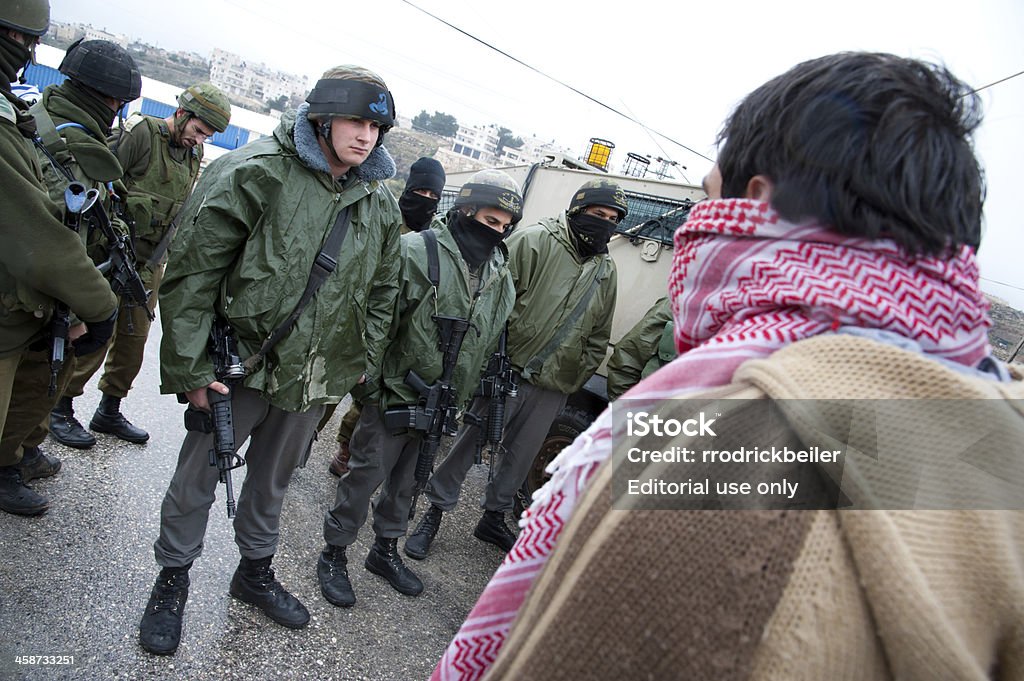 West Bank Palestinians protest Israeli separation wall "Al-Masara, Occupied Palestinian Territories - February 10, 2012: Palestinian activists confront Israeli soldiers to protest the separation wall on a rainy Friday in the West Bank village of Al-Masara." Activist Stock Photo