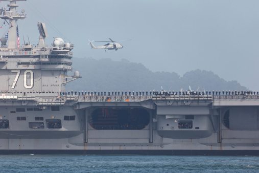 Norfolk, Virginia, USA - May 30, 2023: An American flag waves in the wind on the stern of the USS George H.W. Bush (CVN-77) aircraft supercarrier docked at Naval Station Norfolk while in port.