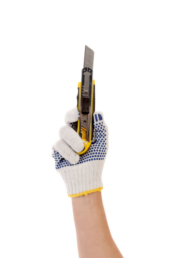 Hand in gloves holds office knife. Isolated on a white background.