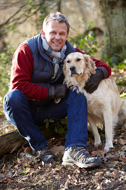 Man Taking Dog On Walk Through Autumn Woods