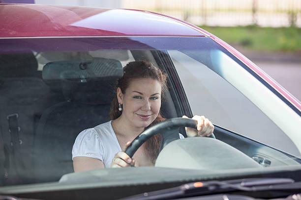 istock Smiling woman holding steering wheel and looking through the windscreen 458848769