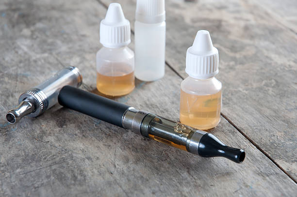 istock Electronic cigarettes and flavor oils on wooden table 458856987