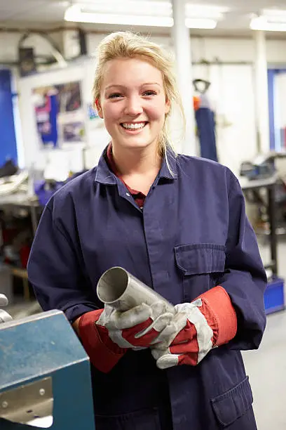 Photo of Female apprentice engineer working on a factory floor