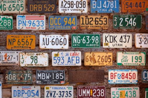 Moab, Utah, USA - May 14, 2013: Old car license registration plates from various US states on a wall.