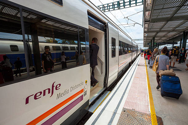 Perpignan, France - July 25, 2011: Exterior view of a train operated by the Spanish company Renfe as it awaits departure at a platform on the route to Barcelona. Passengers can be seen making their way along the platform.