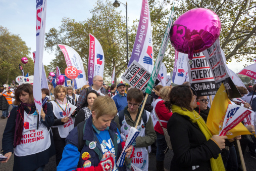 London, England - October 20, 2012: Protesters march against David Cameron's Coalition Government spending cuts that are taking place in the UK public sector. In the image, many nurses are marching in order to save jobs and benefits in the public sector.