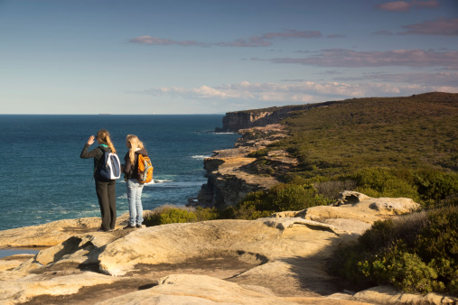Sydney, Australia - July 8, 2013: Two female hikers look towards the sea along the Royal National Park's coastal walk.