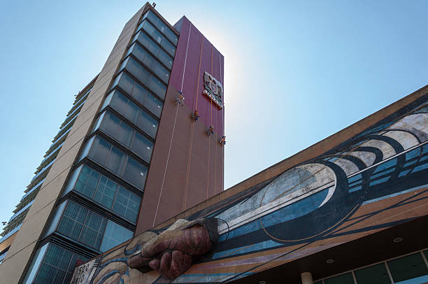 UNAM Rectory Building Mexico City, Mexico - March 24, 2013: Dramatic view of the UNAM (Universidad Nacional Autonoma de Mexico) Rectory Building.At top, painters hung on the wall.A detail of David Alfaro Sequiros (1896-1974) mural painting, at bottom. steeplejack stock pictures, royalty-free photos & images