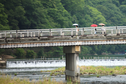 Kyoto, Japan - July 3rd, 2013: Women with parasol walking on the Togetsukyo Bridge, Arashiyama's landmark.