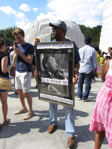 Washington DC, USA-August 24, 2013:  This man holds a sign with a message from Dr. King at the Martin Luther King, Jr. Memorial in remembrance of Dr. Martin Luther King Jr. for the 50th anniversary of the civll rights march on Washington DC.  The original civil rights march took place on August 28, 1963.   The memorial attracts visitors from everywhere.