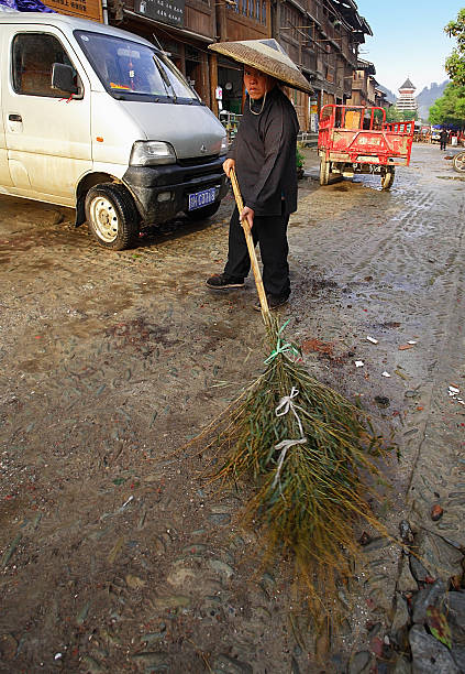 Guizhou Province, China - april 8, 2010: Chinese janitor sweeping the main street of the village of bamboo broom, April 8, 2010. Zhaoxing Dong ethnic minorities village, Liping County.