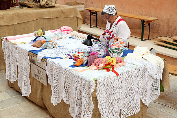Rab, Rab Island, Croatia - July 27, 2013: An old woman selling handmade products from Rab lace during Rab Fiera. The days of the middle ages, “Rapska Fjera”, takes place on the St. Jacob's day, on St. Anna's day and on St. Christopher's day. The Kaldanac, The old town of Rab, is then transformed into a medieval town. Around 400 costumed citizens of Rab, members of various associations are showing the guests  the medieval crafts and how people in the middle ages on the island were working, eating and celebrating. The programme lasts for three days and takes place in the evening hours.