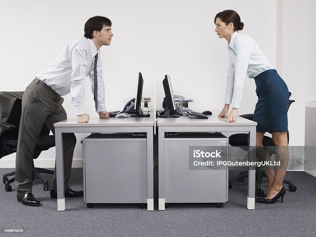 Rival Business Colleagues In Office Side view of a male and female rival business colleagues in office Adult Stock Photo