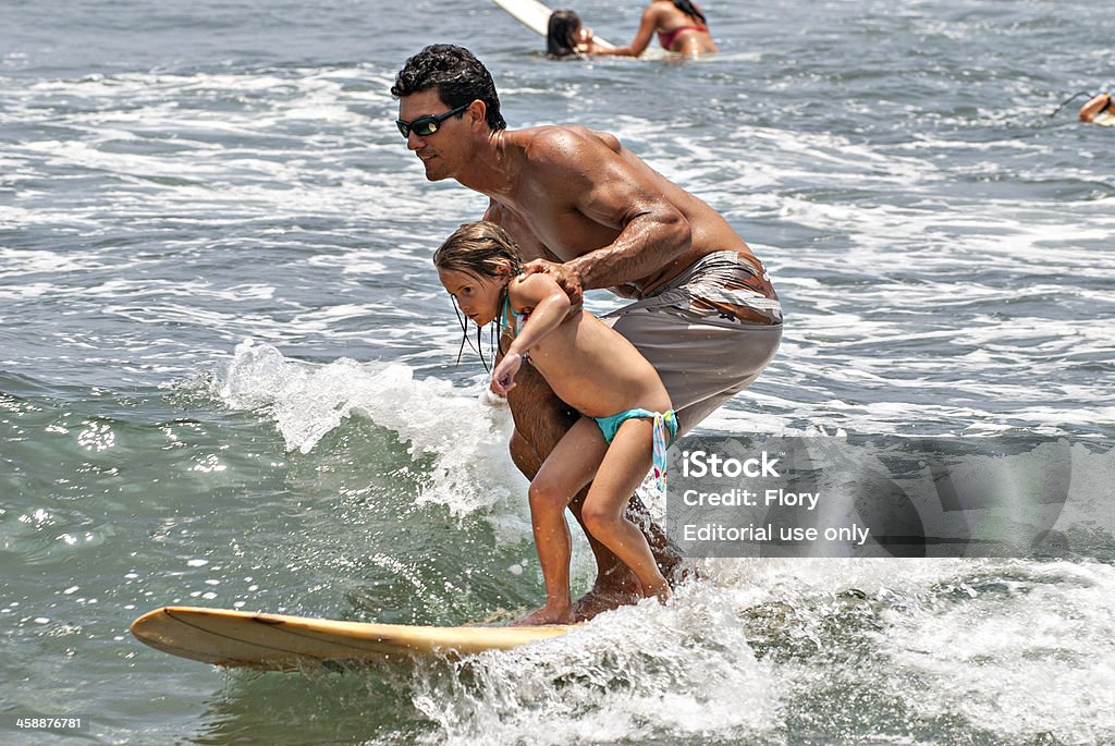 Father and daughter surfers Kahului Hawaii, United States - May 18, 2008: Father and daughter on the surfboard, the father teaches his daughter surfing in the sea in Hawaii. Active Lifestyle Stock Photo