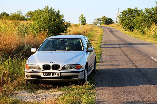 silver bmw 528i se su una strada di campagna - bmw wing badge hood foto e immagini stock