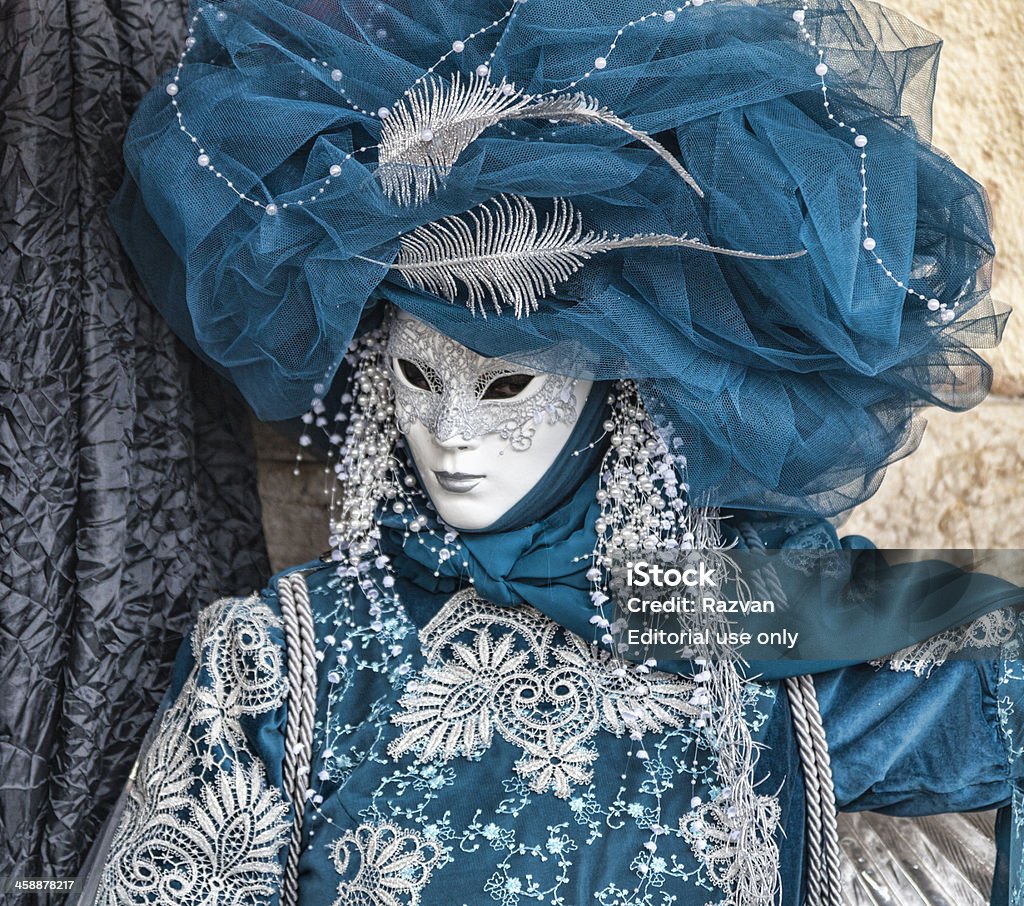 Blue Venetian Disguise Venice, Italy- February 19th, 2012: Environmental portrait of a person disguised in a blue costume with a white mask during the Venice Carnival days. Beauty Stock Photo