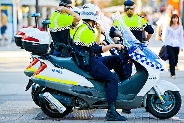 Policemen on motorcycles, Barcelona Barcelona, Spain - October 15, 2012: Two policemen on motorcycles and policewoman patrolling Barcelona street. They wear uniform with sign on their back "Guardia Urbana" , people walking on background. police policewoman women spain stock pictures, royalty-free photos & images