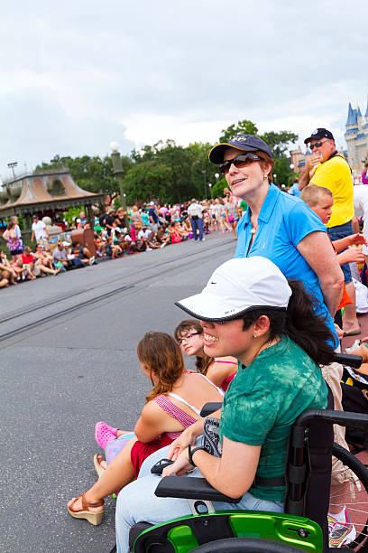 Orlando, USA - August 4, 2013: A girl in a wheelchair is waiting for a parade to start at a very crowded Main Street USA, the entrance to Magic Kingdom amusement park in Walt Disney World and the route of several parades during the day.