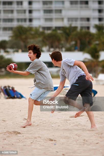 Foto de Garoto Adolescente Capturas Bola Em Jogo De Futebol De Praia e mais fotos de stock de Futebol Americano de Toque