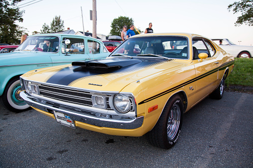 Dartmouth, Nova Scotia, Canada - August 15, 2013: At a public car gathering, a classic Dodge Demon parked in a parking lot with windows down.  Passing street with traffic and people visible in background.