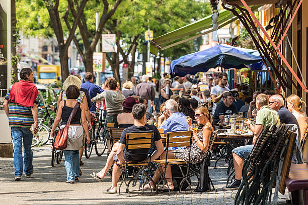 Cafe with many people in Berlin Berlin, Germany - August 10, 2013: Cafe in the Bergmannstreet in Berlin, Germany. Bergmannstrae is a famous street in Kreuzberg / Berlin. People speaking and relaxing at the cafA in summer. restaurant kreuzberg stock pictures, royalty-free photos & images