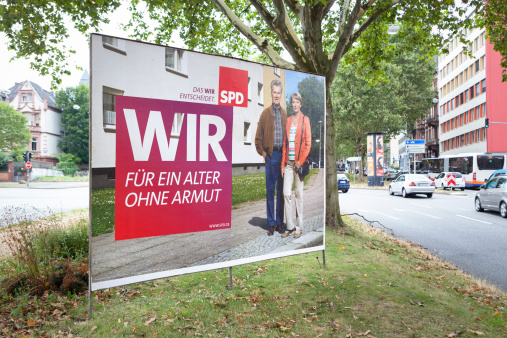 Wiesbaden, Germany - August 9, 2013: Election campaign billboard of the German Social Democratic Party (SPD) in the city center of Wiesbaden. Germany faces federal elections scheduled for September 22. Some passersby and road users in the background.