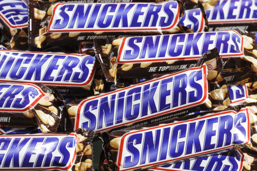 Tula, Russia - January 12, 2013: Closeup of heap of many Snickers candy chocolate bars in market. Full Frame. Snickers bar manufactured by Mars Inc. Mars inc.