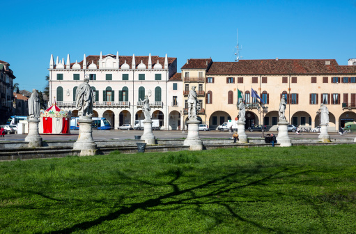 Padua, Italy - March 21, 2013: The statues along the canal in Prato Della Valle with some people walking in the square