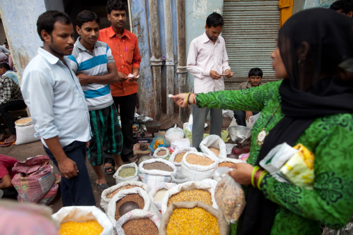 New Delhi, India - August 18, 2013.  An Indian woman buys a small bag of dried lentils from a street side market in the old part of the city.