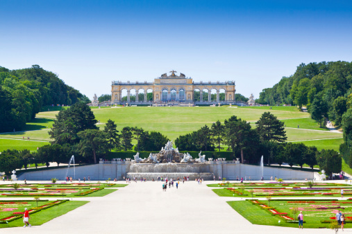 Vlenna, Austria - June 22, 2013: Gardens of SchAnbrunn Palace - View of the Gloriette and the Sun fountain. The SchAnbrunn Palace was an imperial summer residence of the Habsburg monarchs. It is one of the most important cultural monuments in the country and since the 1960s it has been one of the major tourist attractions in Vienna. Tourists are walking around.