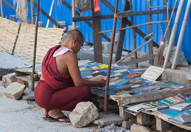 монах-послушник выбрать книгу на уличный рынок. янгон. мьянма. - buddhism monk book zen like стоковые фото и изображения