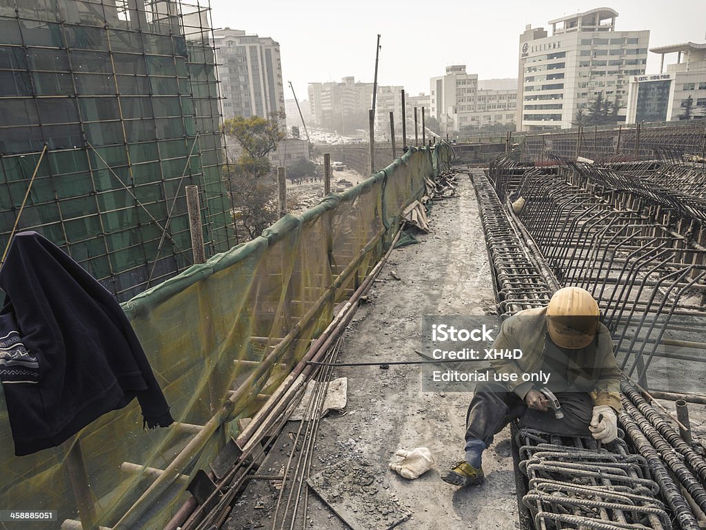 Building city Chengdu, China - January 30, 2013: The migrant workers are working high above the ground for build huge flyovers to alleviate the gridlock in ChengDu YongFeng Road,but the dust brings the big fog to cause huge pollution. Adult Stock Photo