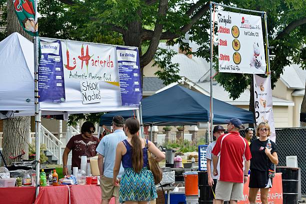 Fort Collins, Colorado, USA - August 18, 2013: People at booths that sell food and drinks at the New West Fest in Fort Collins. New West Fest is an annual street festival with arts, crafts, food, amusement rides, and concerts. 2013 marked its 25th anniversary.