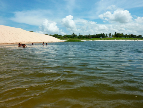 Cumbuco, Brazil - February 02, 2011: funny day at Cumbuco sand dunes. Local kids playing and swimming in the beautiful lake surrounded by big sand dunes and tropical vegetation.