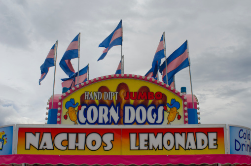 Poncha Springs, United States - August 2, 2013: Corn Dogs County Fair Display - The local county fair is always a fun place to grab junk food of all kinds, including corn dogs, nachos and lemonade.  Here's a decorative booth on midway advertising all those items and more!