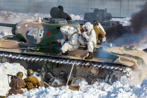 Kubinka, Moscow region, Russia - February 23, 2013: Russian commandos in camouflage on the T-34. German tank burning in the background. Soviet tank is T-34-85. Fascist tank is LT vz.38 (Panzerkampfwagen 38(t), Pz.Kpfw.38(t)). Reconstruction of the Second World War battle with the participation of tanks, armored vehicles and infantry. The battle is going in the Moscow region known as \