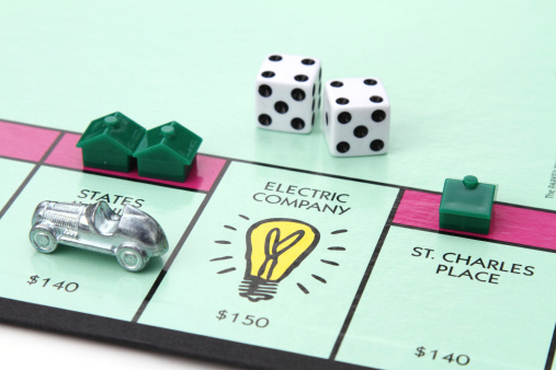 West Palm Beach, USA - August 15, 2013: A partial view of a Monopoly game board showing the  Electric Company space. Dice, houses and the Race Car game piece are also placed on the game board. Monopoly is owned and manufactured by Hasbro.