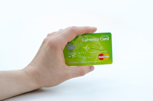 Derby, England, United Kingdom - August 18, 2013: A close up of a hand, that is holding a green Master Card credit card. Photographed in front of a white background in a photo studio.