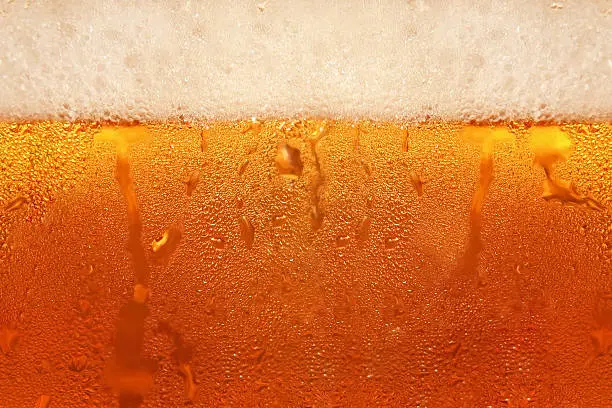 Beer foam in glass taken closeup as background.